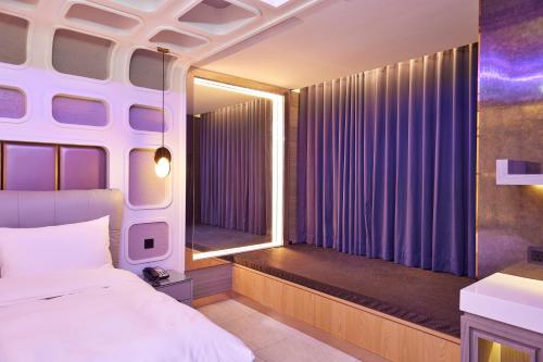 a bedroom with a bed and a window with purple curtains at Motel Well in Zhubei