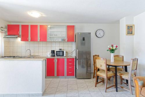 a kitchen with red cabinets and a table with chairs at Apartment Ana-Rapavel in Višnjan
