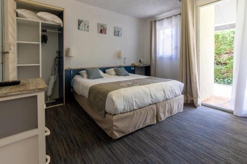 a bedroom with a large bed and a large window at Logis Hôtel de la Plage in La Cotinière