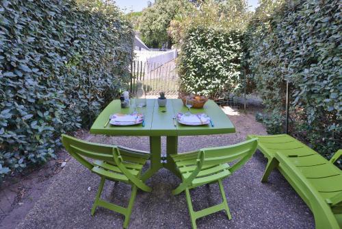a green table and two chairs in a garden at Logis Hôtel de la Plage in La Cotinière
