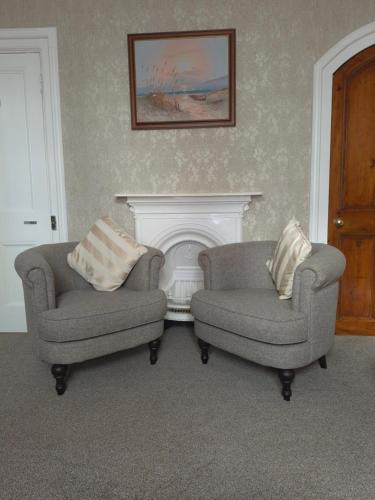 a living room with two chairs and a fireplace at St David's Guesthouse in Haverfordwest
