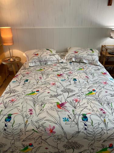 - un lit avec une couette et des oiseaux dans l'établissement Le bon coin, à Périssac