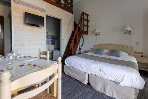 a hotel room with a bed and a table with a dining room at Logis Hôtel de la Plage in La Cotinière