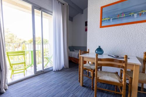 a room with a table and chairs and a balcony at Logis Hôtel de la Plage in La Cotinière