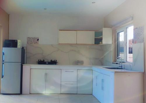 格兰贝伊Coastal Bliss Apartment Mauritius的厨房配有白色橱柜和白色冰箱