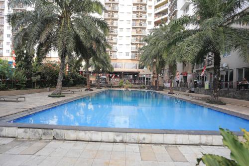 a large blue swimming pool with palm trees and a building at Collection O Serviced Apartmen Mutiara Kota in Bekasi
