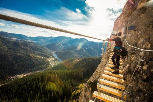 a man on a rope bridge on a mountain at Red Lake Apartman in Lacu Rosu