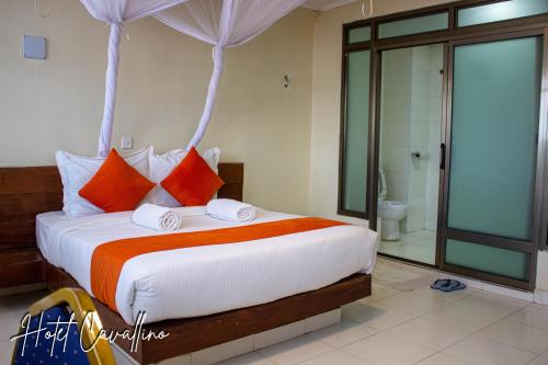 a bedroom with a bed with orange and white pillows at Hotel Cavallino in Kakamega