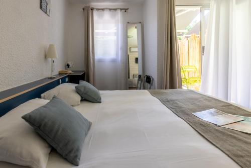 a large white bed with two pillows on it at Logis Hôtel de la Plage in La Cotinière