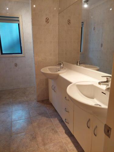 a bathroom with two sinks and a mirror at Waiwera Clifftop - Eagle's Rest in Waiwera