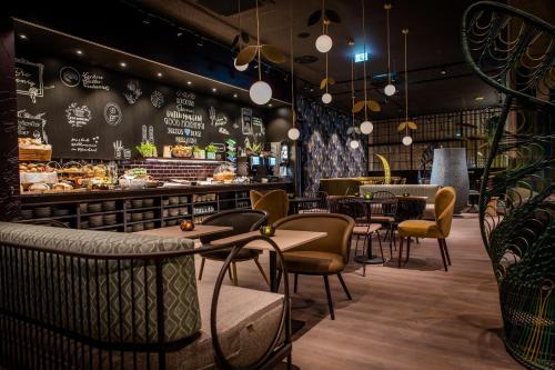 a restaurant with tables and chairs and a counter at Motel One München Hauptbahnhof in Munich