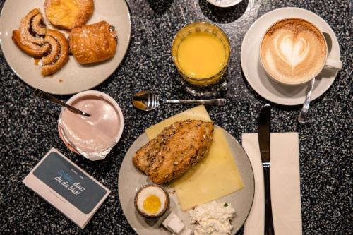 a table with plates of food and a cup of coffee at Motel One München Hauptbahnhof in Munich