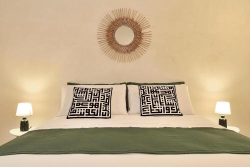 a bed with two pillows and a mirror on the wall at La casa dei Limoni con piscina Noto in Noto