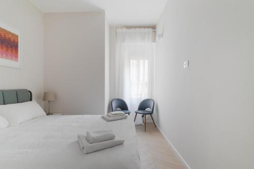 a white bedroom with two chairs and a bed at Loreto - Buenos Aires - Moderno bilocale in Milan
