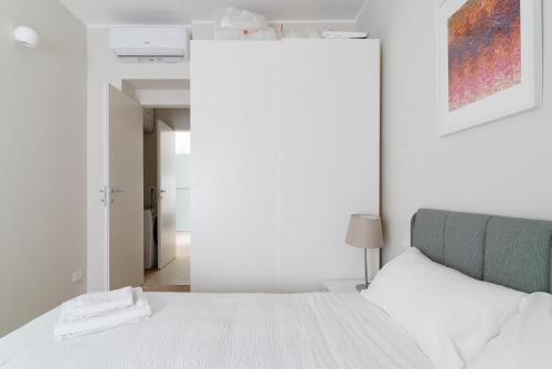 a white bedroom with a bed and a hallway at Loreto - Buenos Aires - Moderno bilocale in Milan