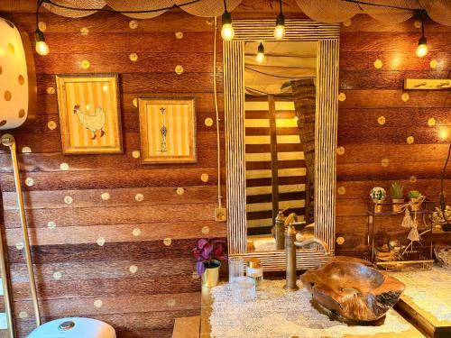 a bathroom with a mirror on a wooden wall at Bali Cozy Bungalows, Nusa Dua Benoa in Nusa Dua