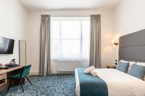 um quarto de hotel com uma cama, uma escrivaninha e uma janela em The Chapter Hotels - The J Hyde Park em Londres