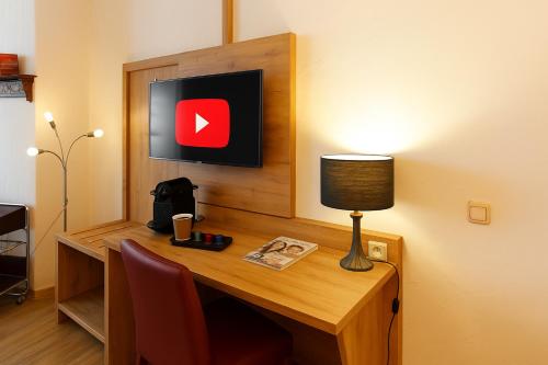 a desk with a lamp and a monitor on a wall at Zum Treppche Hotel Garni in Gladenbach