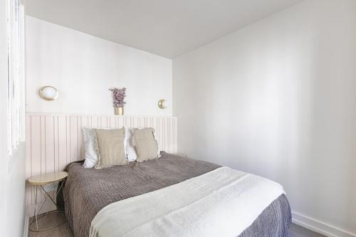 une chambre blanche avec un grand lit avec des oreillers dans l'établissement Appartement de Charme rue Lafayette 4P-1BR, à Paris