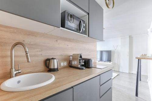 un comptoir de cuisine avec un évier et un micro-ondes dans l'établissement Appartement de Charme rue Lafayette 4P-1BR, à Paris
