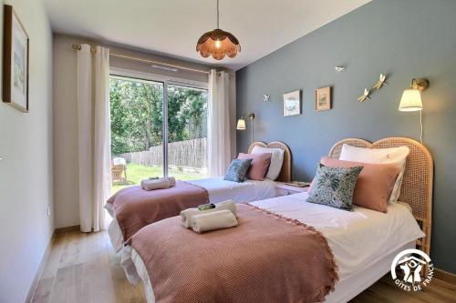 two beds in a room with a window at Gîte Hent Sirius 5 pers. in Sarzeau