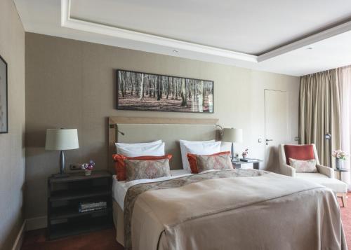 a bedroom with a large bed and a chair at Althoff Seehotel Überfahrt in Rottach-Egern