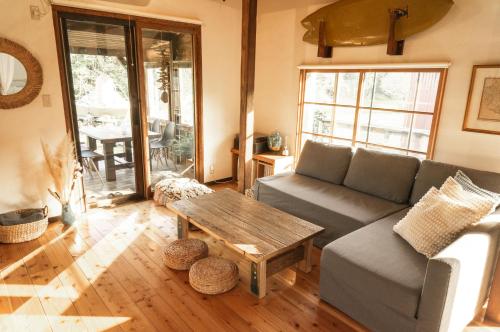 a living room with a couch and a table at Yamakujira 焚火とBBQを楽しめる海辺プライベートコテージ 山鯨荘 in Minamiboso