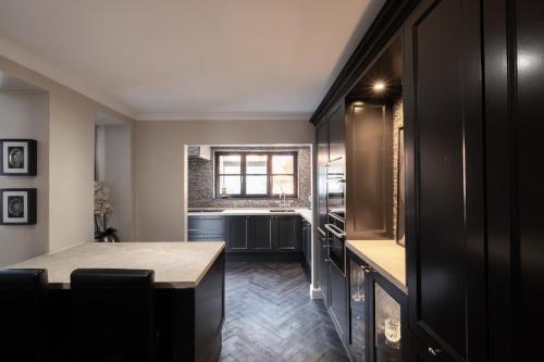 a kitchen with black cabinets and a wooden table at Luxe city villa te Hasselt in Hasselt