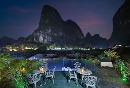 a resort with a pool and mountains at night at Lanshan Moon Resort in Yangshuo