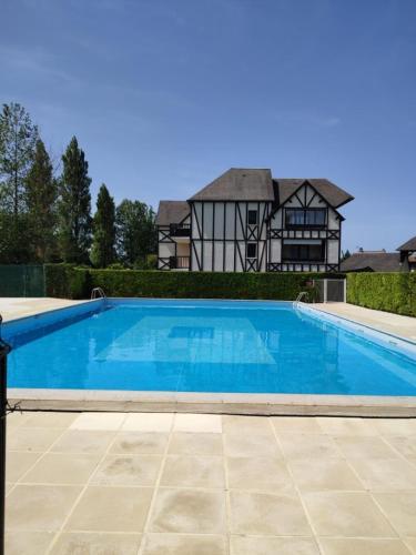 une grande piscine bleue devant une maison dans l'établissement Casa Romantica, à Cabourg