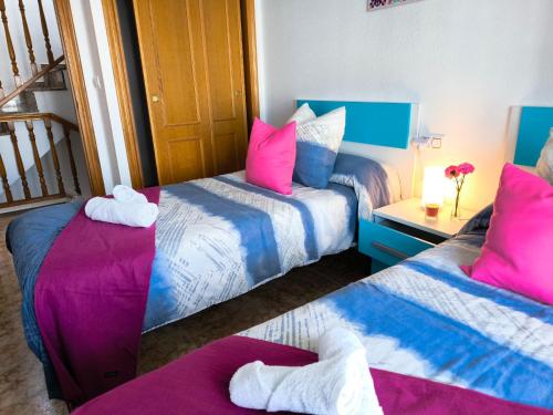 two beds in a room with pink and blue at Modern Duplex with Solarium Community Pool in Orihuela Costa in Orihuela