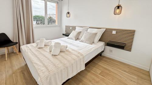 a bedroom with a bed with white sheets and a window at Appartement a quelques minutes à pieds des plages in Fréjus