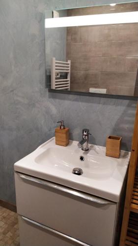 une salle de bains avec un lavabo blanc et un miroir dans l'établissement Appartement climatisé avec terrasse 4 à 6 couchages à 600m du centre thermal, à Lamalou-les-Bains