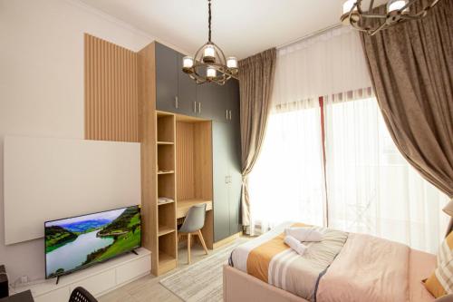 a bedroom with a bed and a flat screen tv at Cozy Studio for Daily Rental Warsan in Dubai