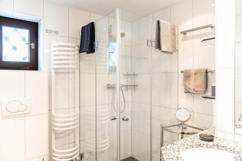 a white bathroom with a shower and a sink at Ferienhaus Frühholz - Fewo Alpspitz in Grainau