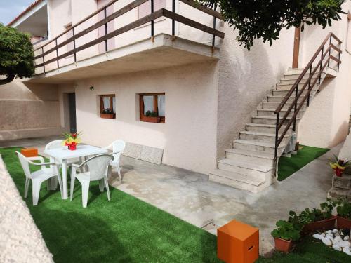 a patio with a table and chairs and a staircase at Casa MedeFaby in S'archittu Cuglieri