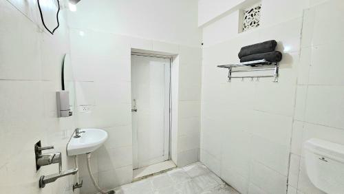 a white bathroom with a sink and a toilet at Elephant House Boutique Stays- BHU- BLW in Varanasi