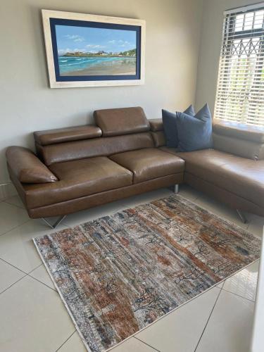 a brown leather couch in a living room with a rug at Oceanway Self-catering Accommodation in Gonubie