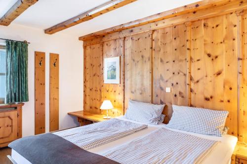 a bedroom with a wooden wall with a bed at Ferienhaus Frühholz - Fewo Alpspitz in Grainau