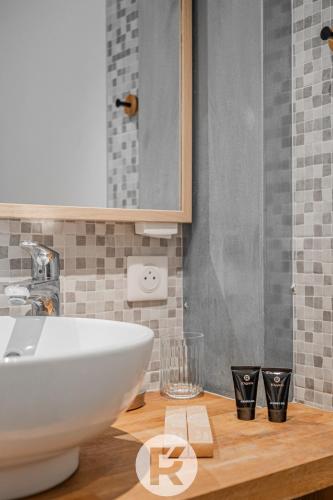 une salle de bain avec un lavabo blanc sur un comptoir en bois dans l'établissement R'Apparts T2 La Halte Savoyarde, à Aix-les-Bains