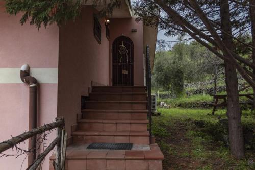 a front door of a pink house with stairs at Casa vacanze Etna in Santa Maria di Licodia
