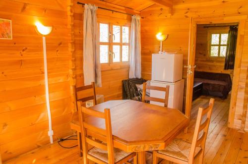 a dining room with a table and a refrigerator at Le Chalet De Louyère in Saint-Salvadour