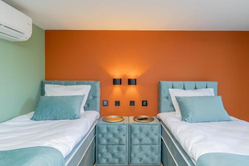 two beds in a room with an orange wall at Villa Meer en Duin in Noordwijkerhout
