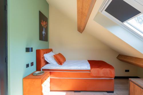 a bedroom with an orange bed in a attic at Villa Meer en Duin in Noordwijkerhout