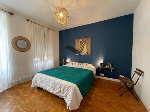a bedroom with a bed and a blue wall at Cocon Bleu - Maison idéalement située avec jardin in Rochefort