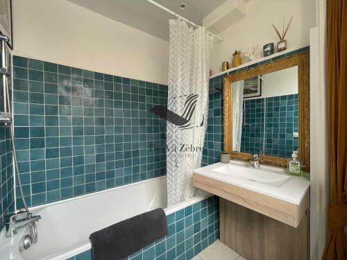 a blue tiled bathroom with a sink and a mirror at Cocon Bleu - Maison idéalement située avec jardin in Rochefort