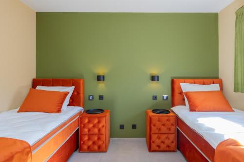two beds in a room with orange and green walls at Villa Meer en Duin in Noordwijkerhout