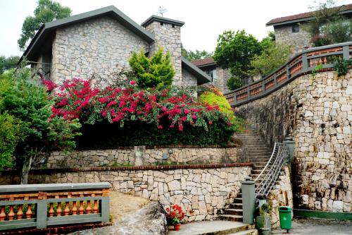 a stone retaining wall with a staircase and flowers at Mountain Club Resort Munnar in Chinnakanal