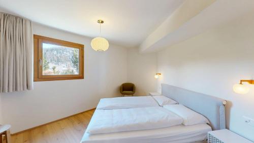 a bedroom with a white bed and a window at Leonard in Celerina