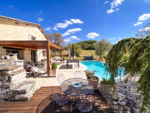 un patio avec une table et des chaises à côté d'une piscine dans l'établissement Casa Guillarmou - Évasion Enchantée avec Piscine Chauffée, Spa & Clim - Vue Exceptionnelle, à Castelnau-de-Montmiral